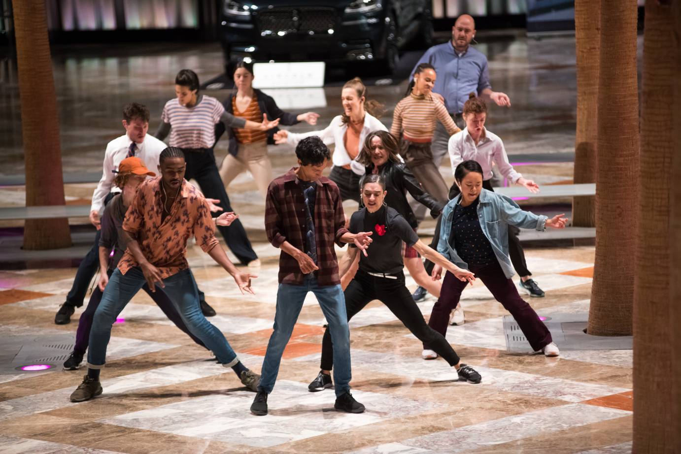 A clump of people extend their arms while dancing in a mall