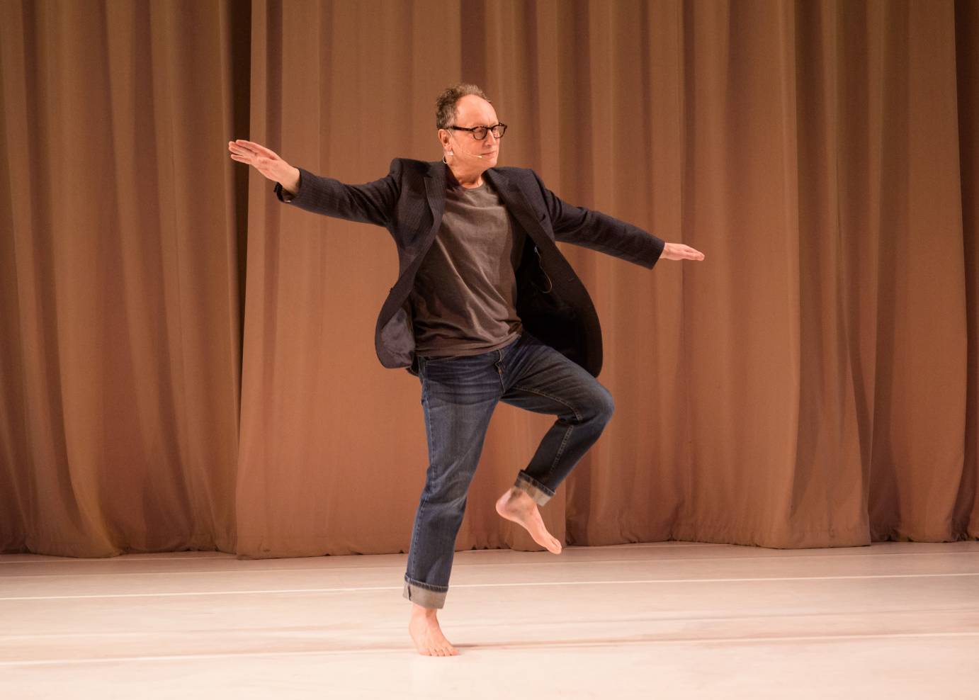 In barefeet and a sports coat, Paul Lazar lifts a leg and extends his arms