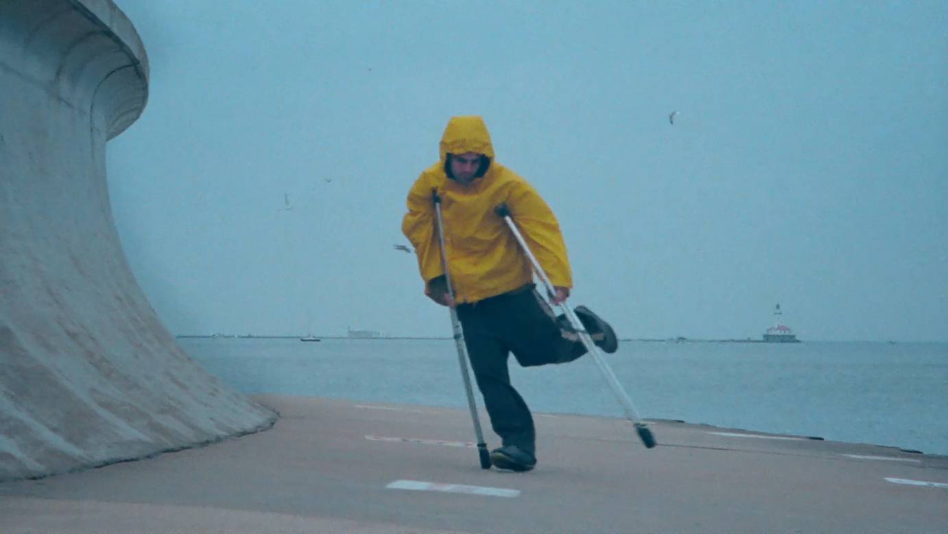 Bill Shannon in a yellow rain slicker, dancing with his crutches