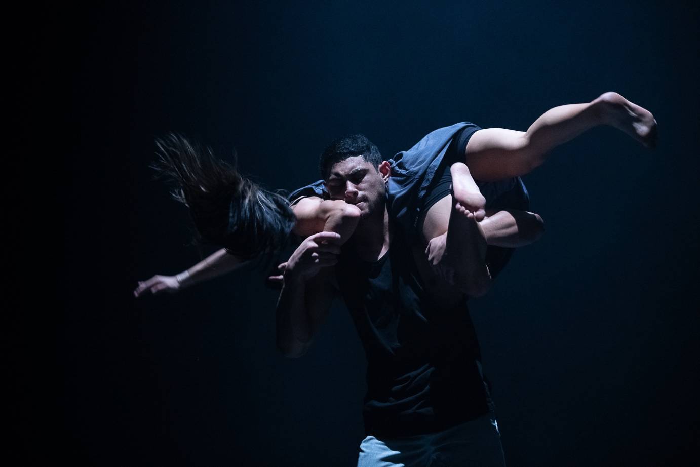 A man lifts a woman across his back