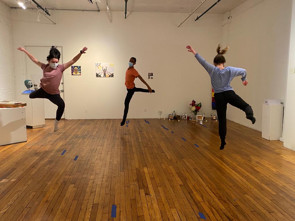 Three dancers leap through the air in a circle