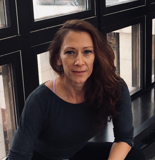 A portrait of Blakely. She wears her long hair down and sits in front of windows. 