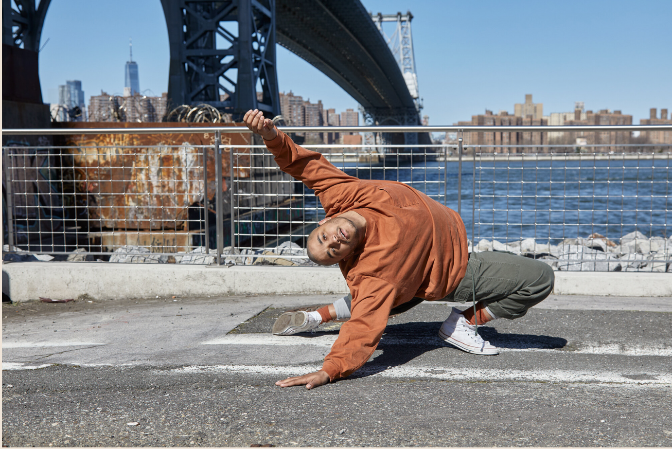 against a city scape, a handsome young man stretches low on the pavement. he seems full of hope and promise