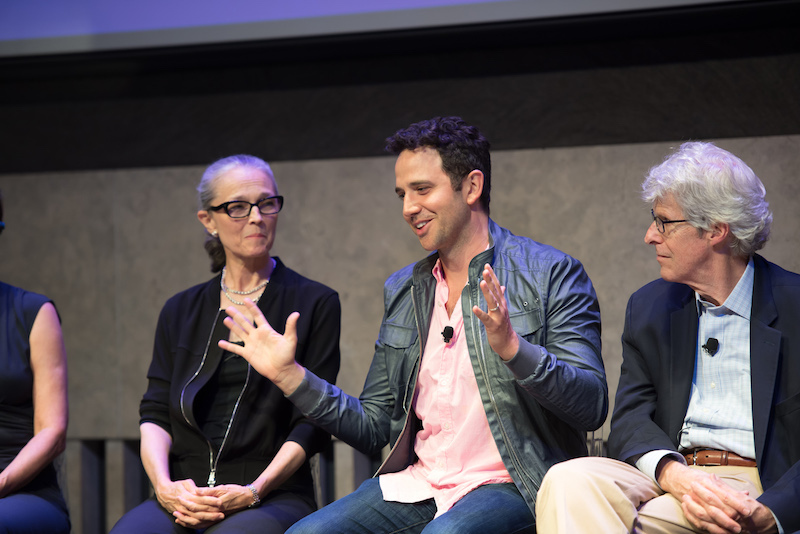 A close up of a panelist talking animatedly while two others observe