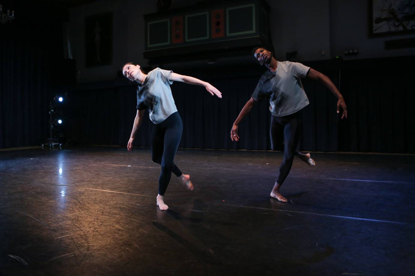 A woman and a man tilt side as one foot hangs by their ankles