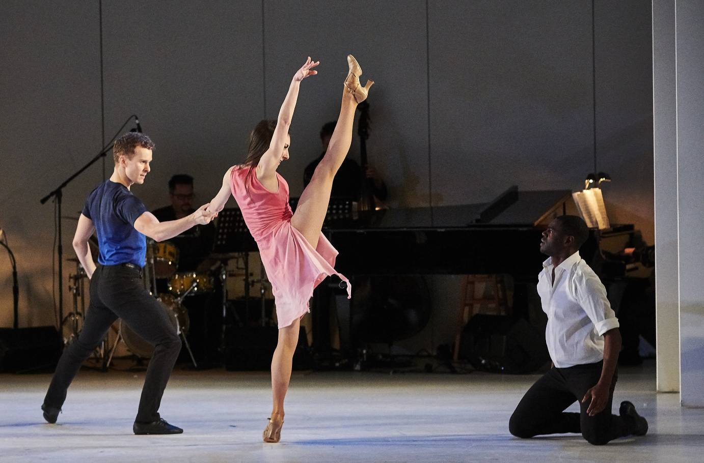 A woman kicks as she holds on to a man as another watches