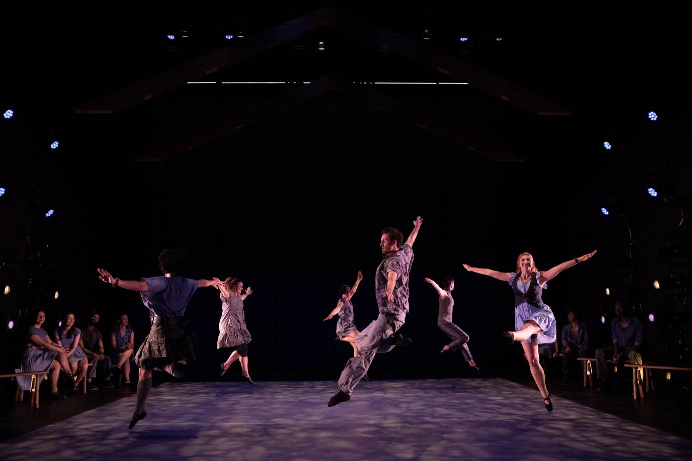 more exuberant leaps performed in a circle by men and women of the two companies as their friends on benches on either side of the circle of jumpers watch 