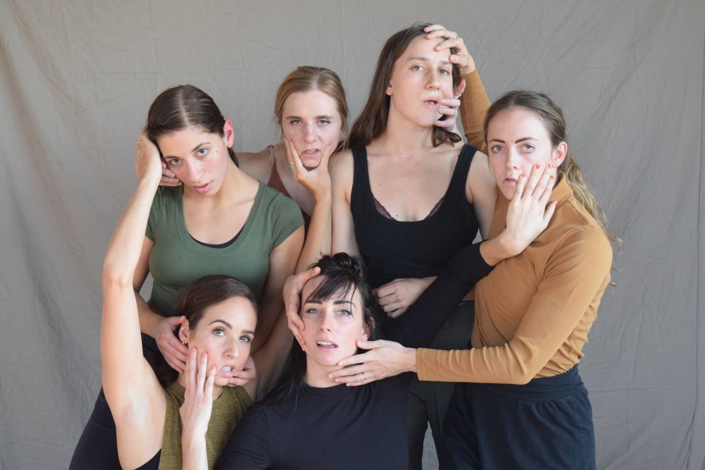 Six women hold onto each other's faces