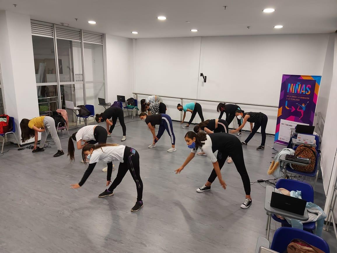 Girls stand with their legs apart and fold forward as part of Vive Bailando's STEM and dance initiative