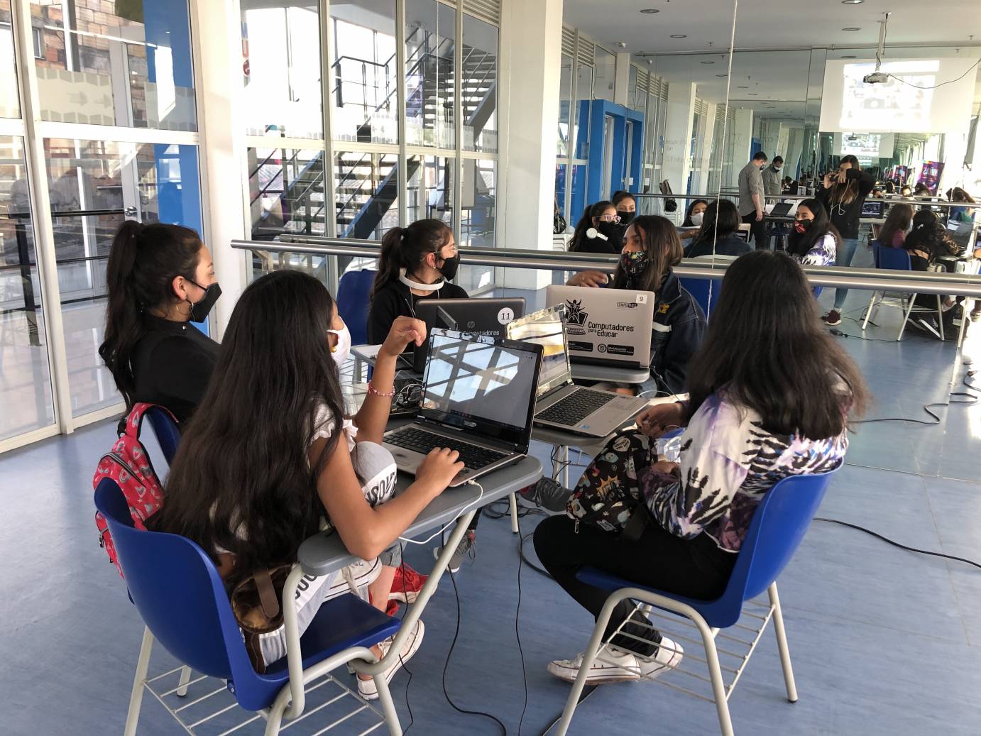 Girls gather around a desk with laptops as part of Vive Bailando's STEM and dance initiative