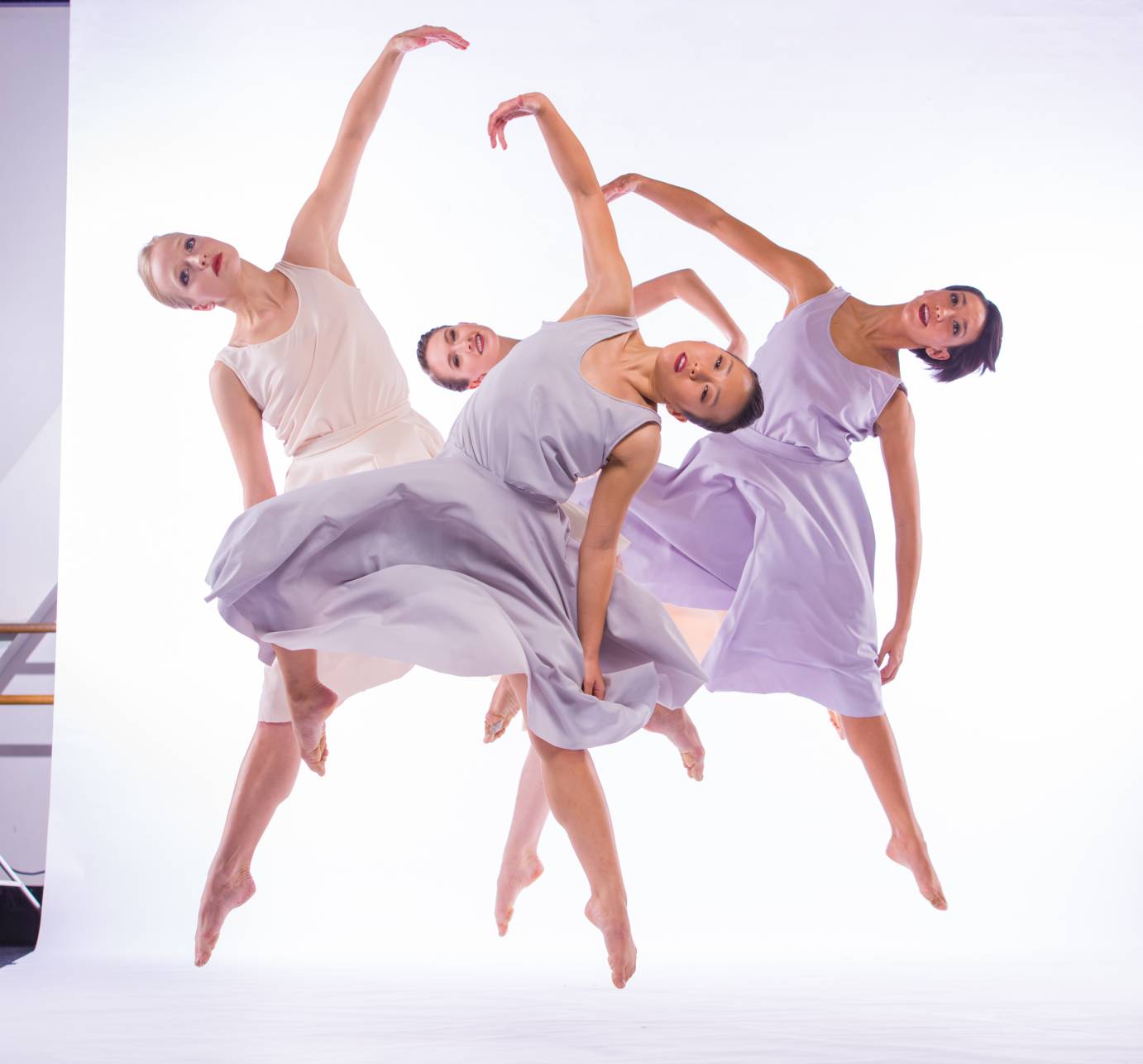 Four women in jumps with their legs in second position and their bodies tipped to the side