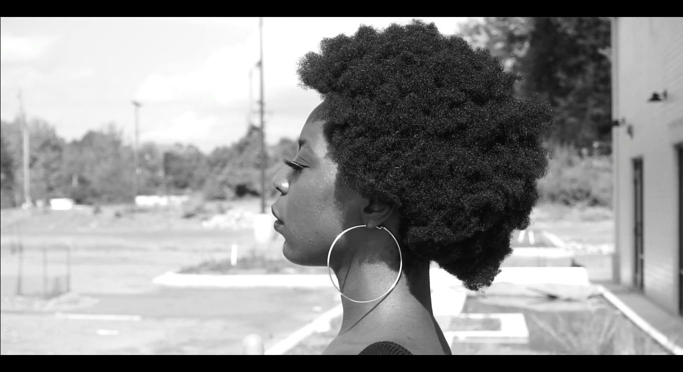 April Watson in profile against a background of trees and parking lots