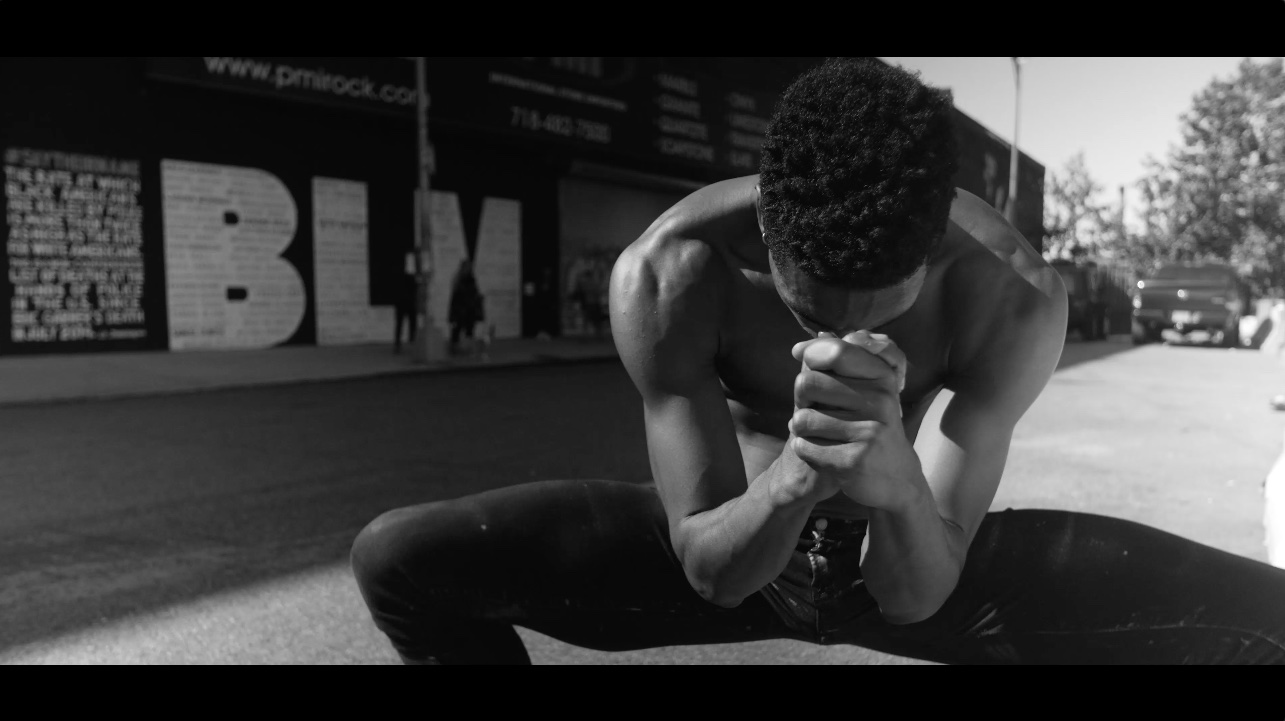 Brandon Gray clasps his hands together in a prayer in front of a BLM sig