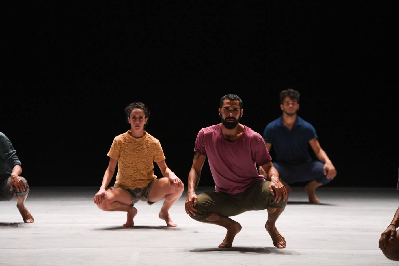 Dancers in street wear kneel with hands on their knees