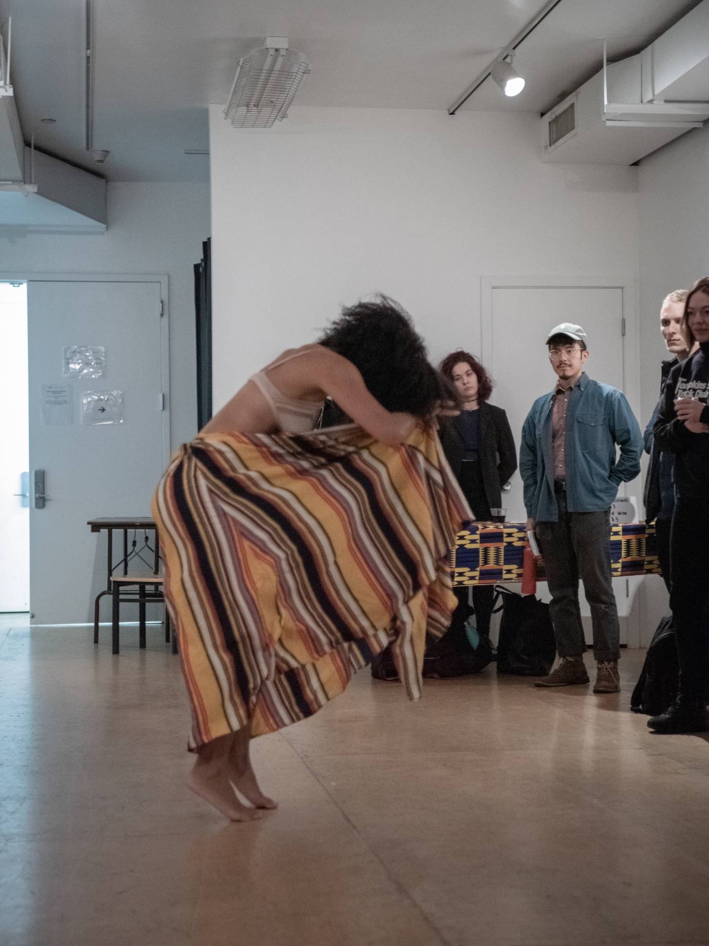 A woman in a striped skirt hunches over, her face hidden