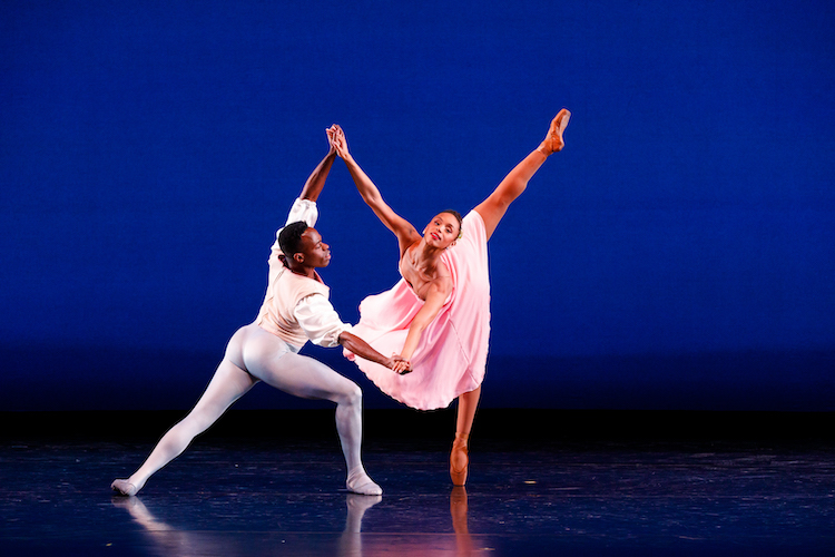 a Black balletic couple, male and female, the man lounging forward in a plie supports his female partner by the arms as she dives forward in a deep arabesque