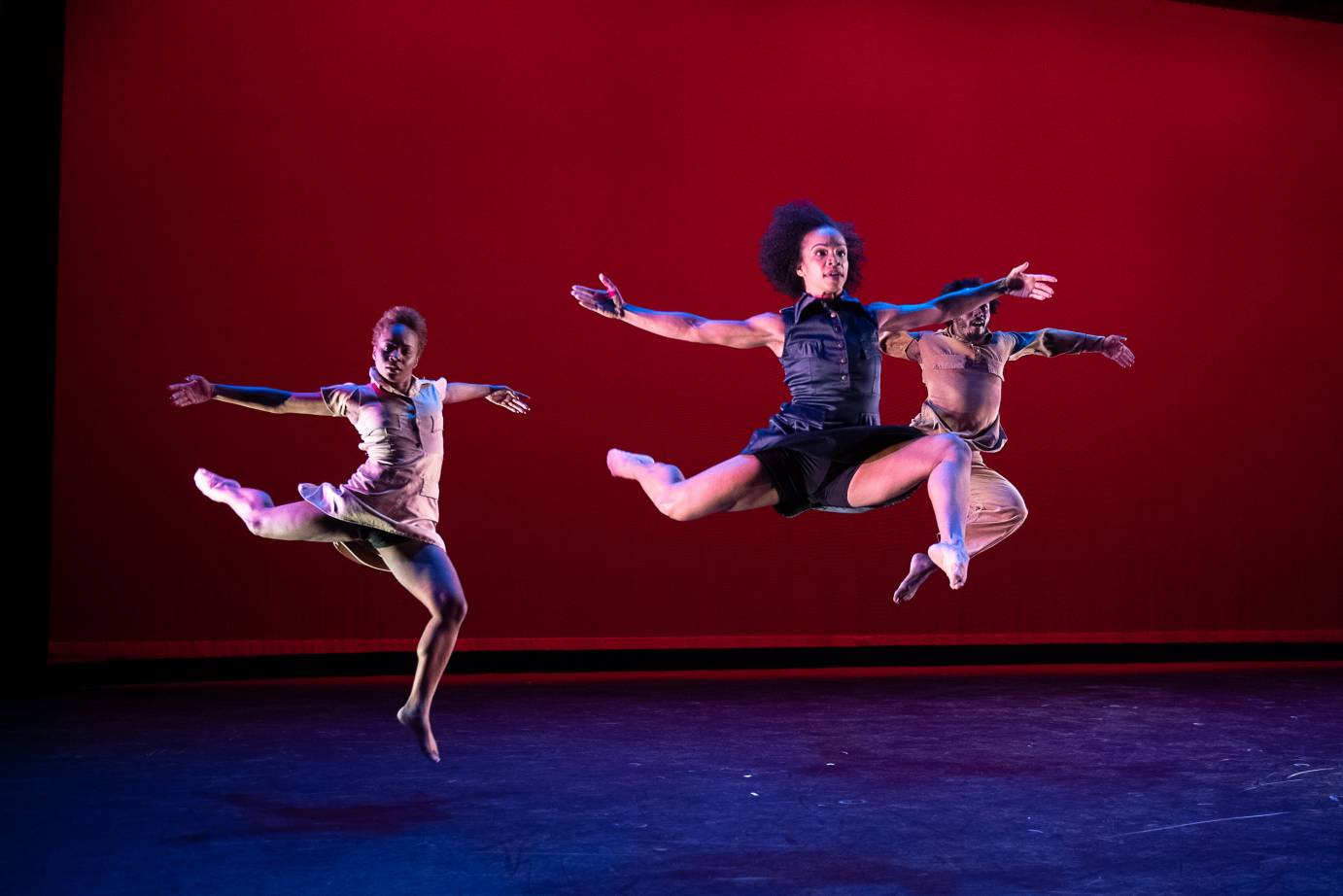 Three dancers soar through the air