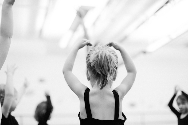 Young dancer put their arms above their head