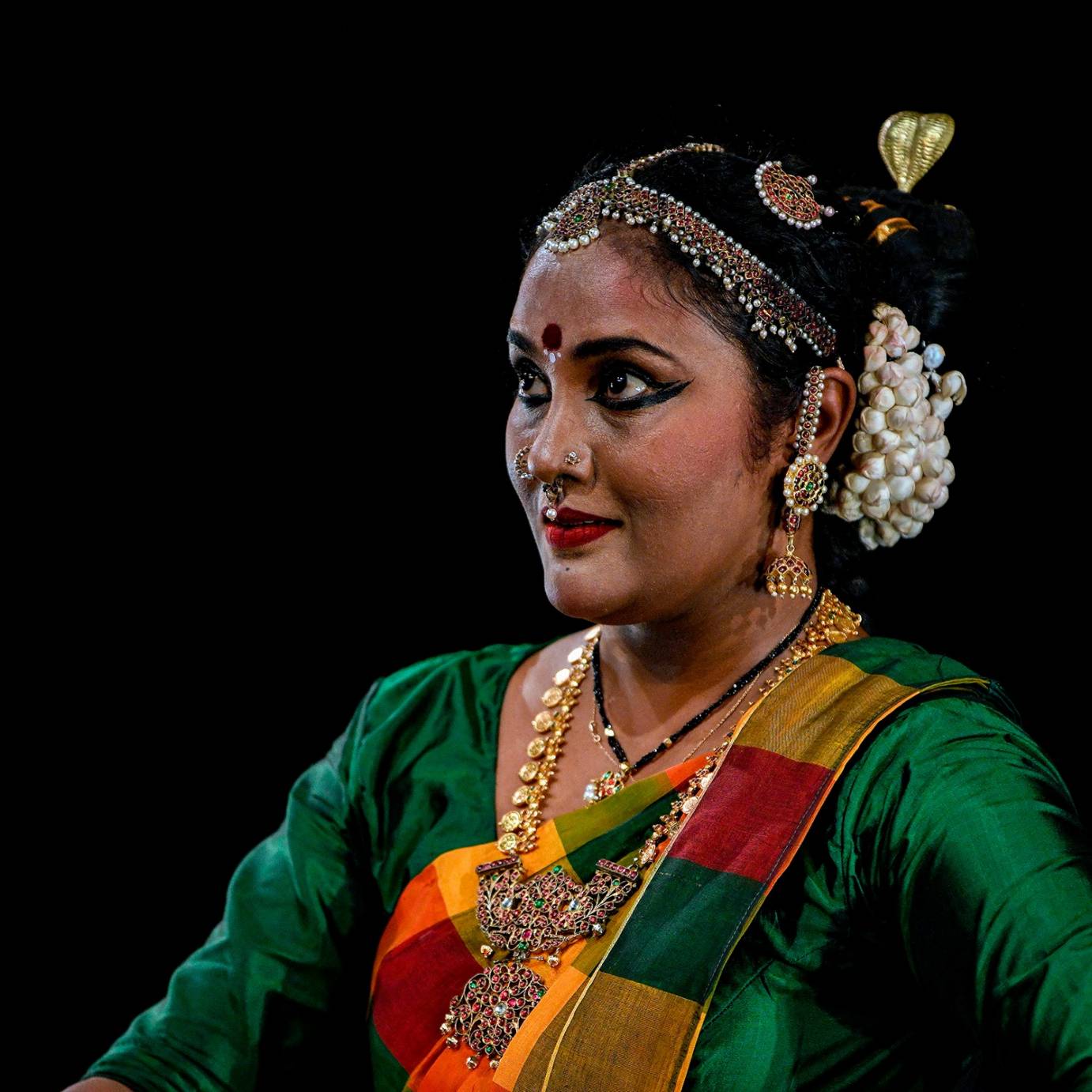 The wide eyed look of a beautiful Indian dancer with jewels adorning her scalp, ears,and napeof necke