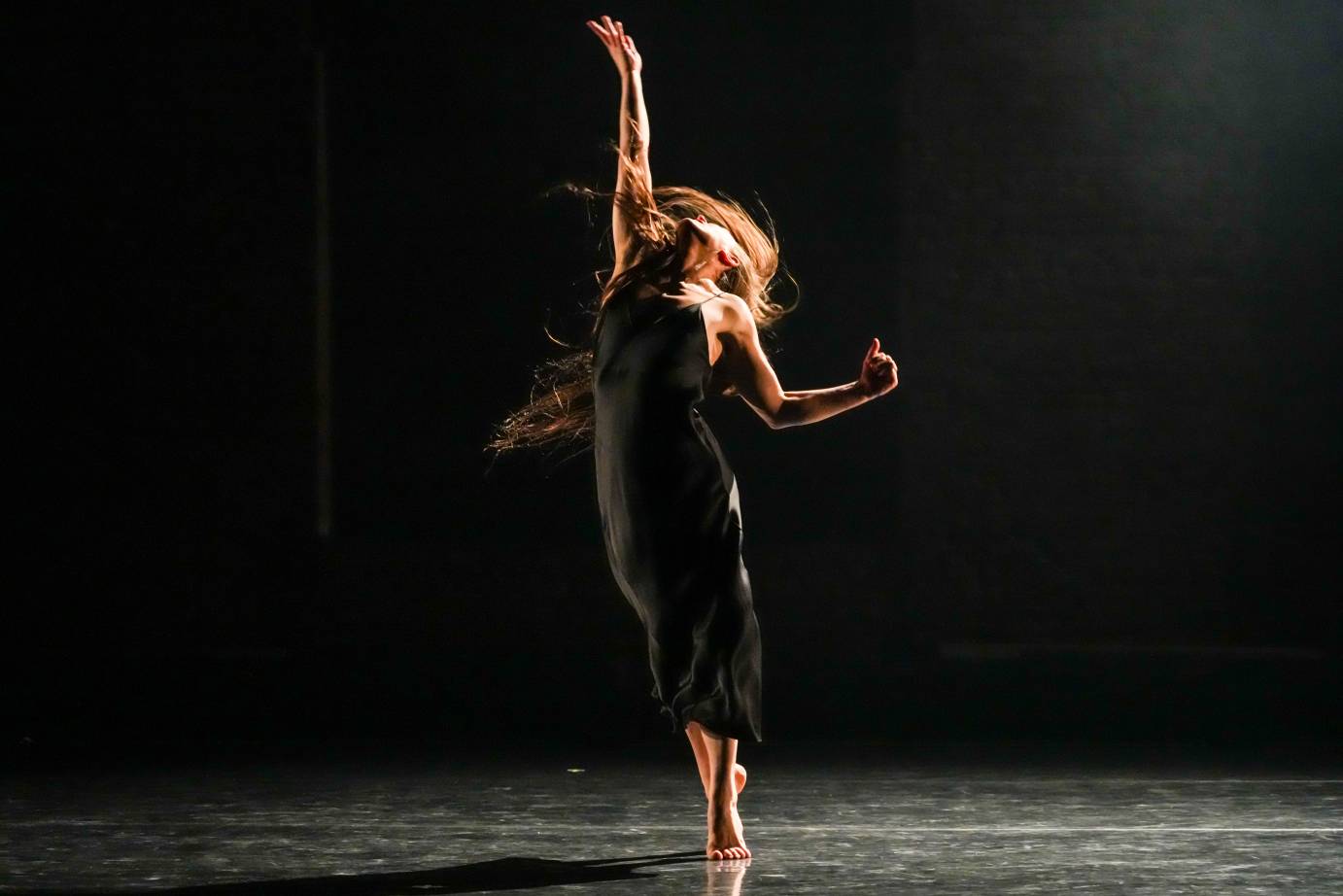 Woman with thigh-length hair stretched to the ceiling. On releve with right arm fully stretched to the ceiling. 