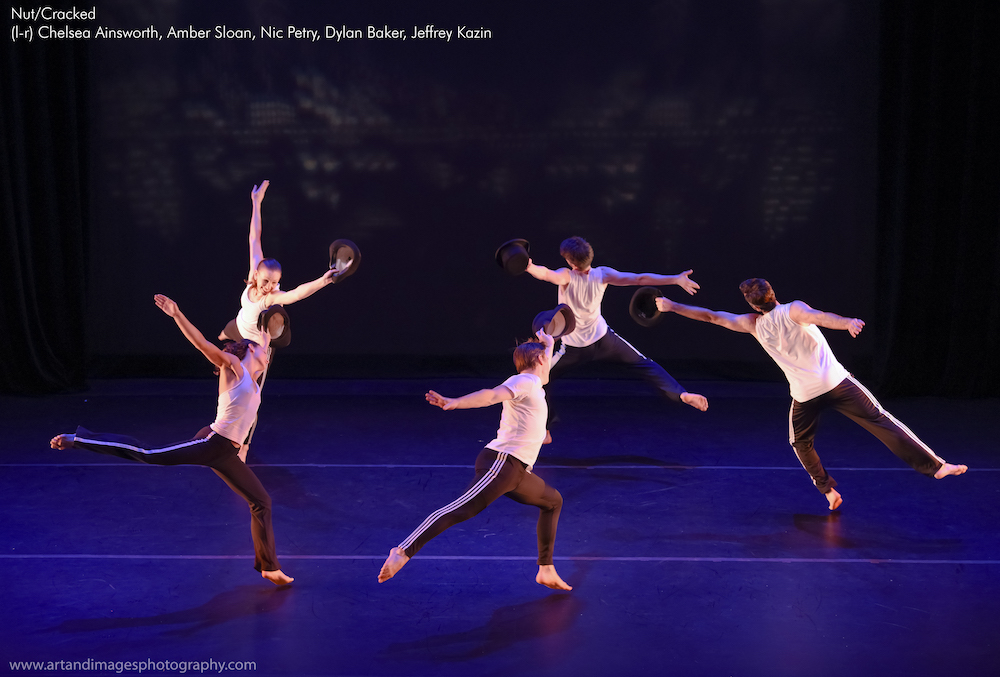 the company in white tshirts and black pants jumps in a circle formation joyously, the hold bowler hats in one hand 