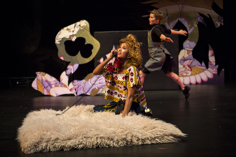 A woman on the shag rug sits on her knees as she talks into an old rotary-dial telephone. A dance skims the floor with a small jump in the background.