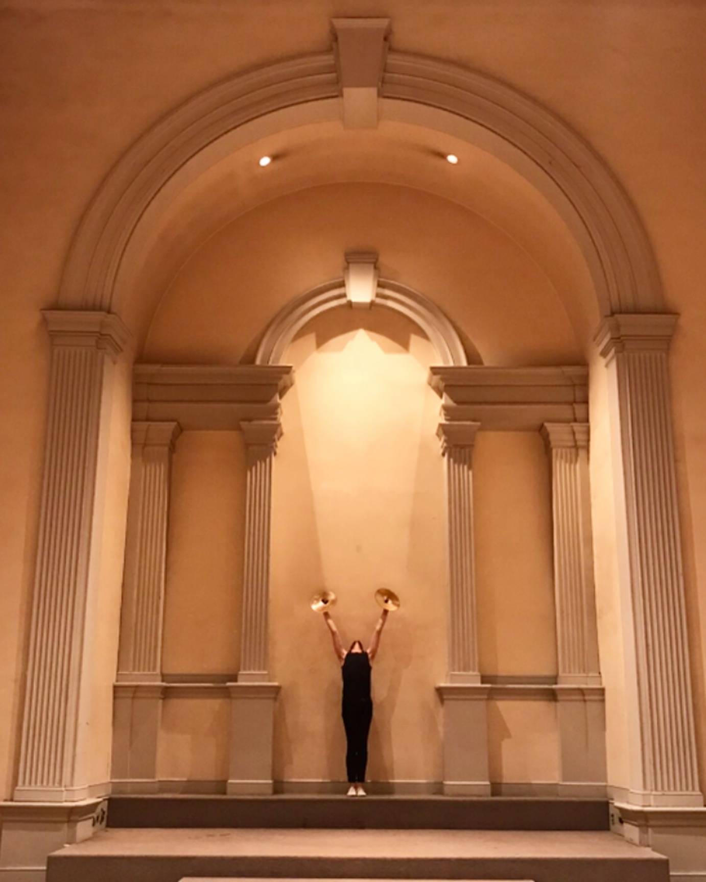 A man stands in a nave, lifting two symbols in the air