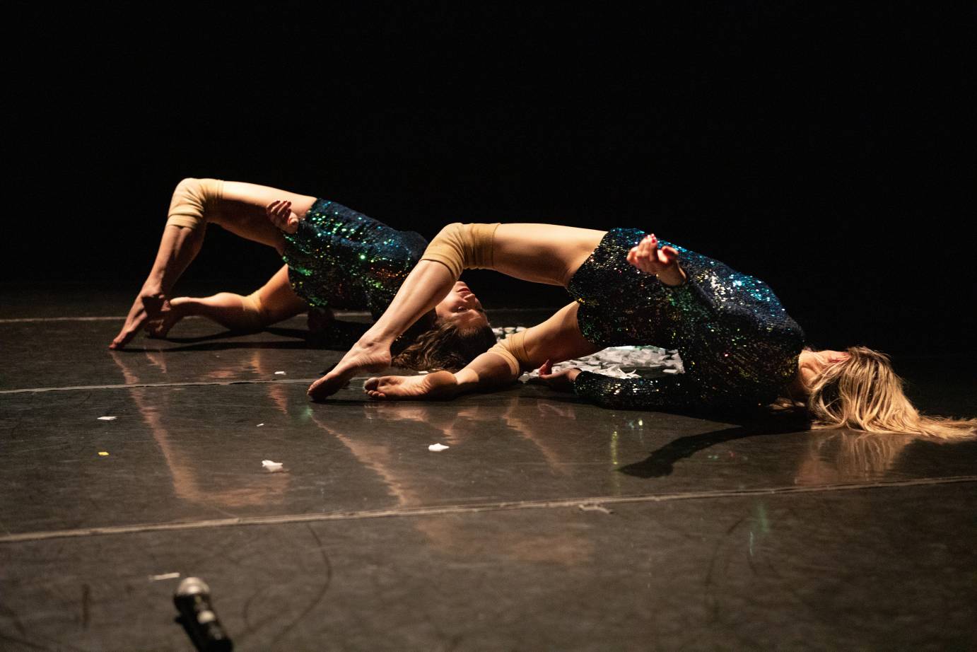 Two women arch their backs while balancing on their toes and head