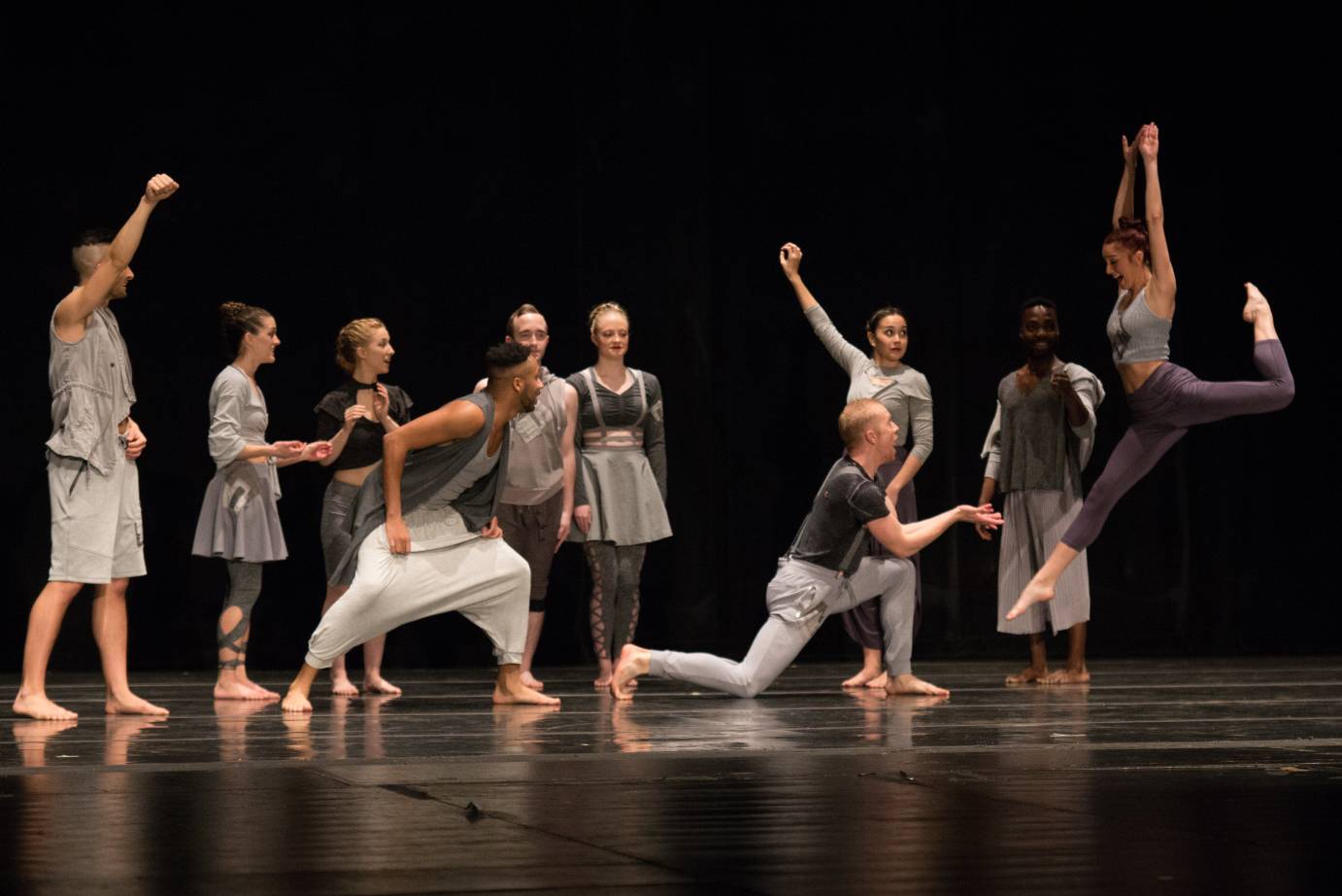 A crowd of happy dancers with some lifting arms while others