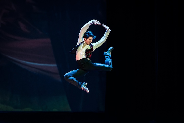 a Spanis Dancer performs a stag leap in the air... he's caught in the photo at the leaps highest moment