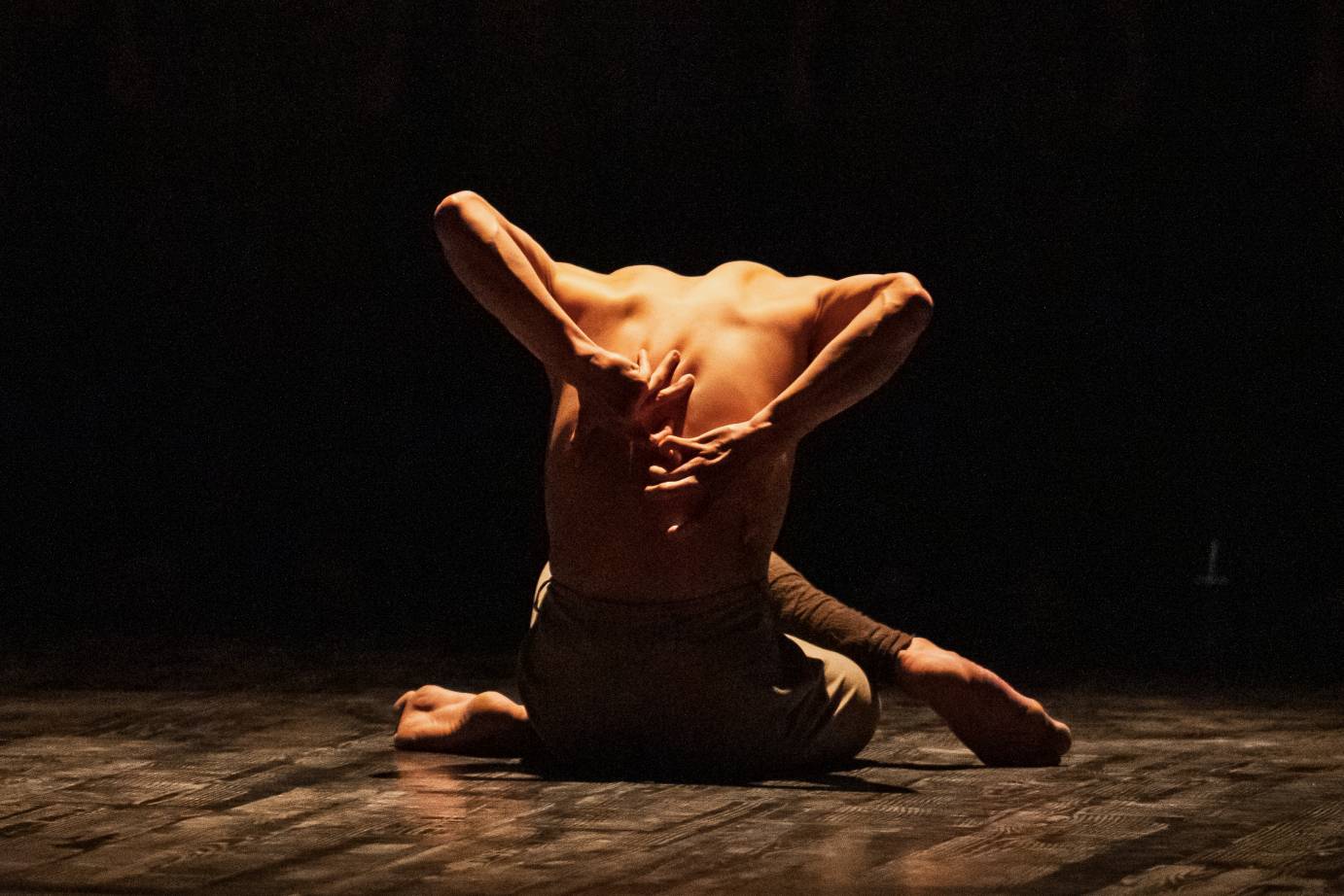 man, backlit, shirt less, grabbing at his spine 