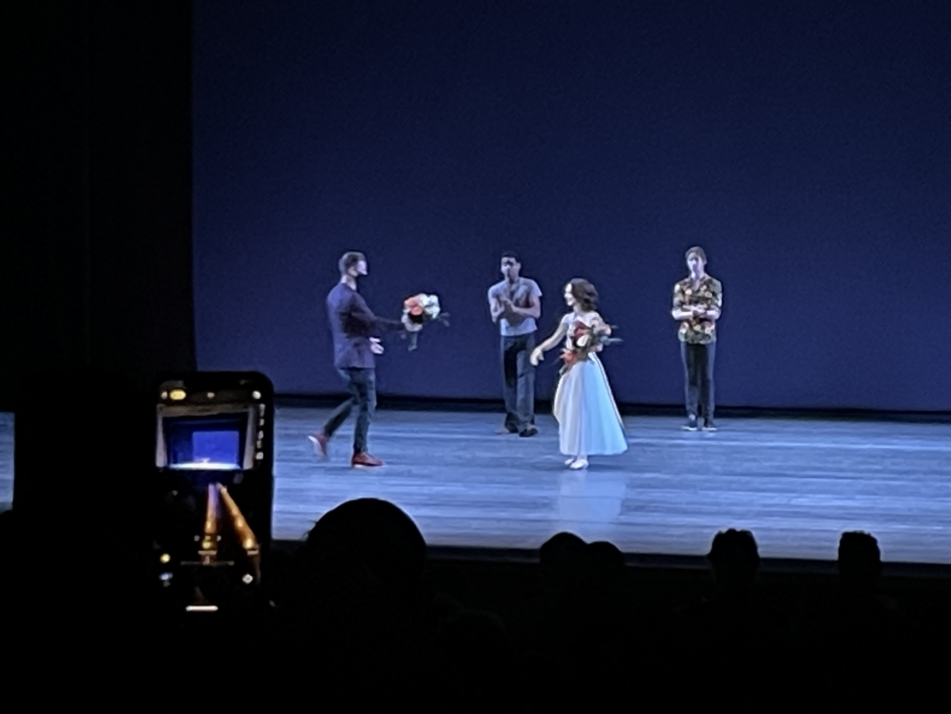 In a blue romantic-length tutu, Lauren Lovette accepts a bouquet of flowers. Dancers behind her applaud.