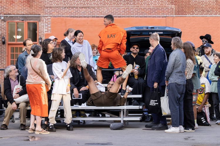 dancers and audience gather together as if in a tailgaiting party. 