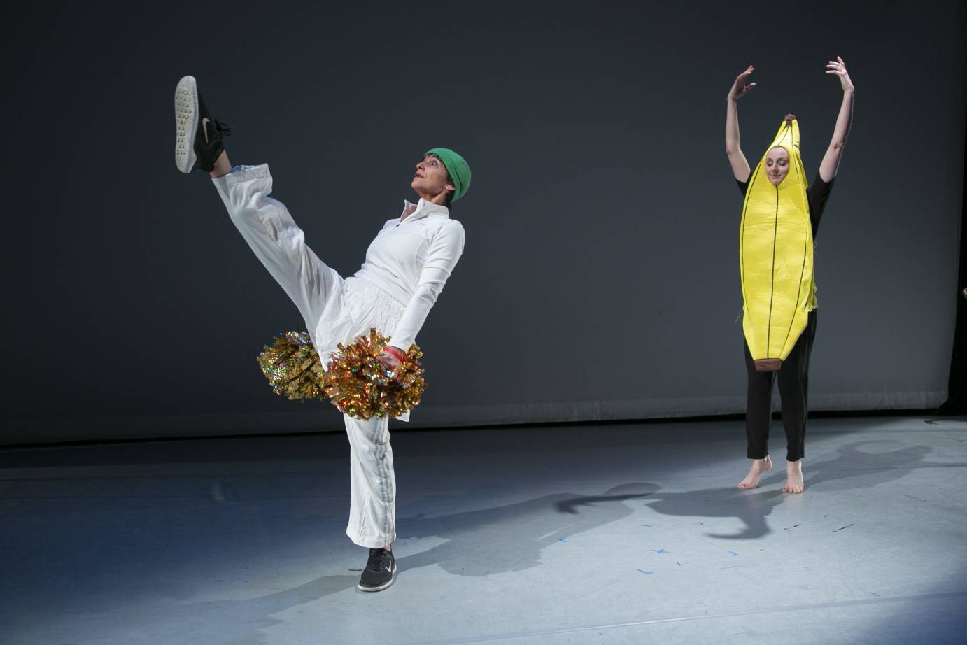 Women dressed as a cheerleader and a banana, respectively, dance on a diagonal