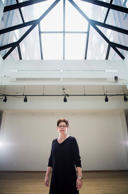 Gina Gibney standing beneath a skylight within Gibney Dance at 280 Broadway.