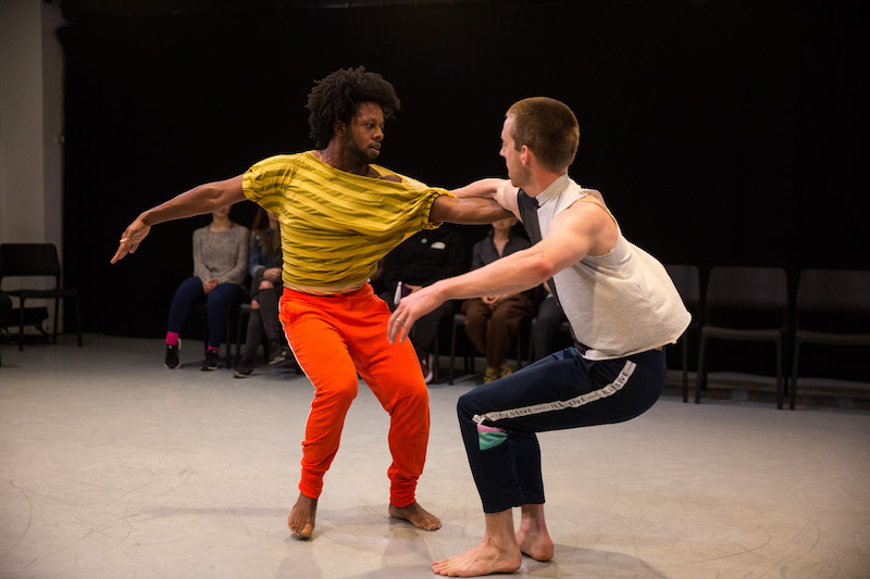 Two men grab onto to one another's arms while their knees are deeply bent.