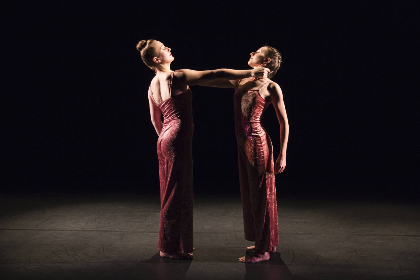 Two women in pink velour jumpsuits hold each other's necks