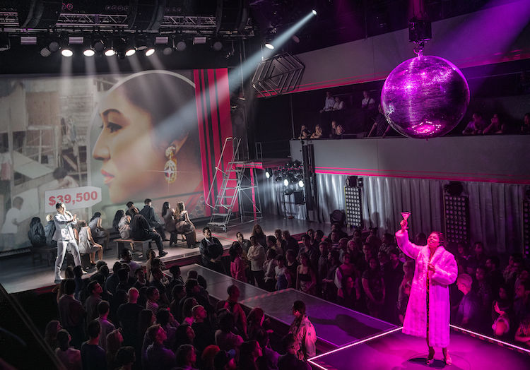 Imelda is donned in a white fur standing at the very front of the stage area. Her hand, holding a martini glass, is raised up as if to toast. At the back of the stage is a price tag that illustrates her excessive spending