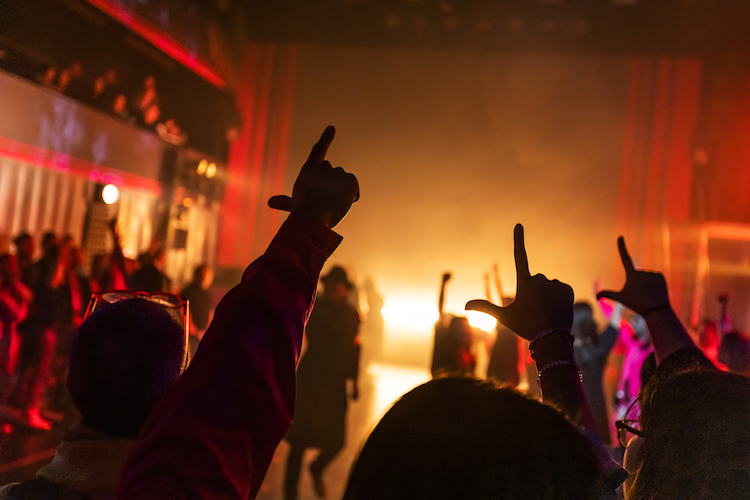 shot of audience members raising their arms in dance guided by the cast of Here Lies Love