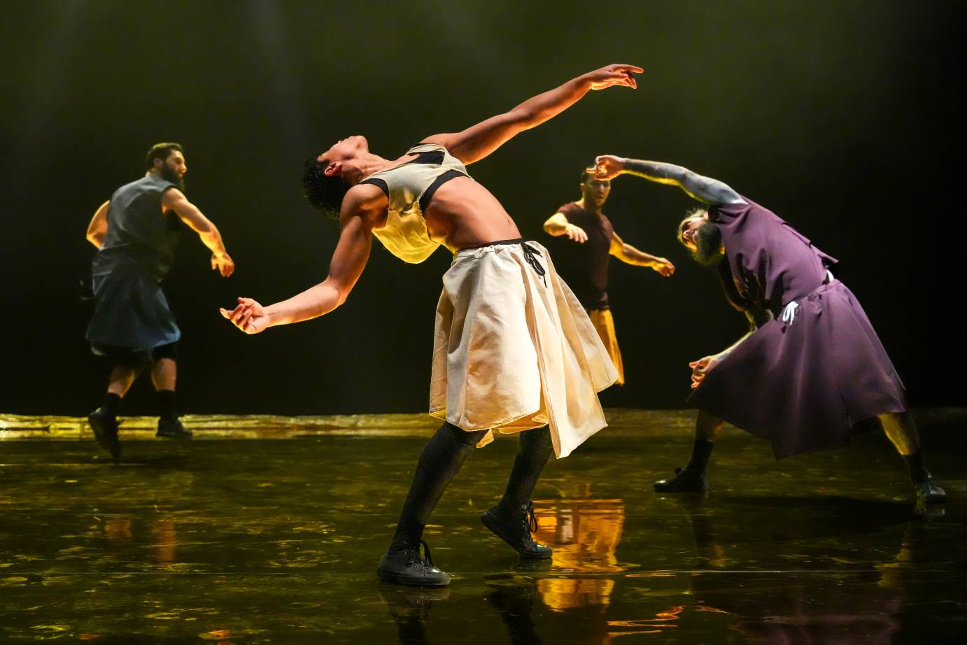 four dancers in a beautiful configuration of movement, The central figure in white leans backwards exposing muscles in their arms and stomaches