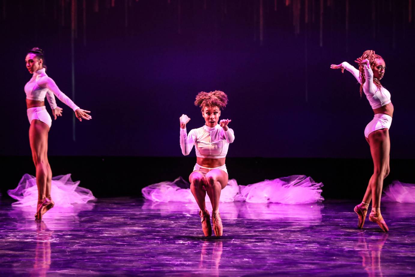 Three women in shorts and midreiff tops of white satin performing jazzy hiple pointe work