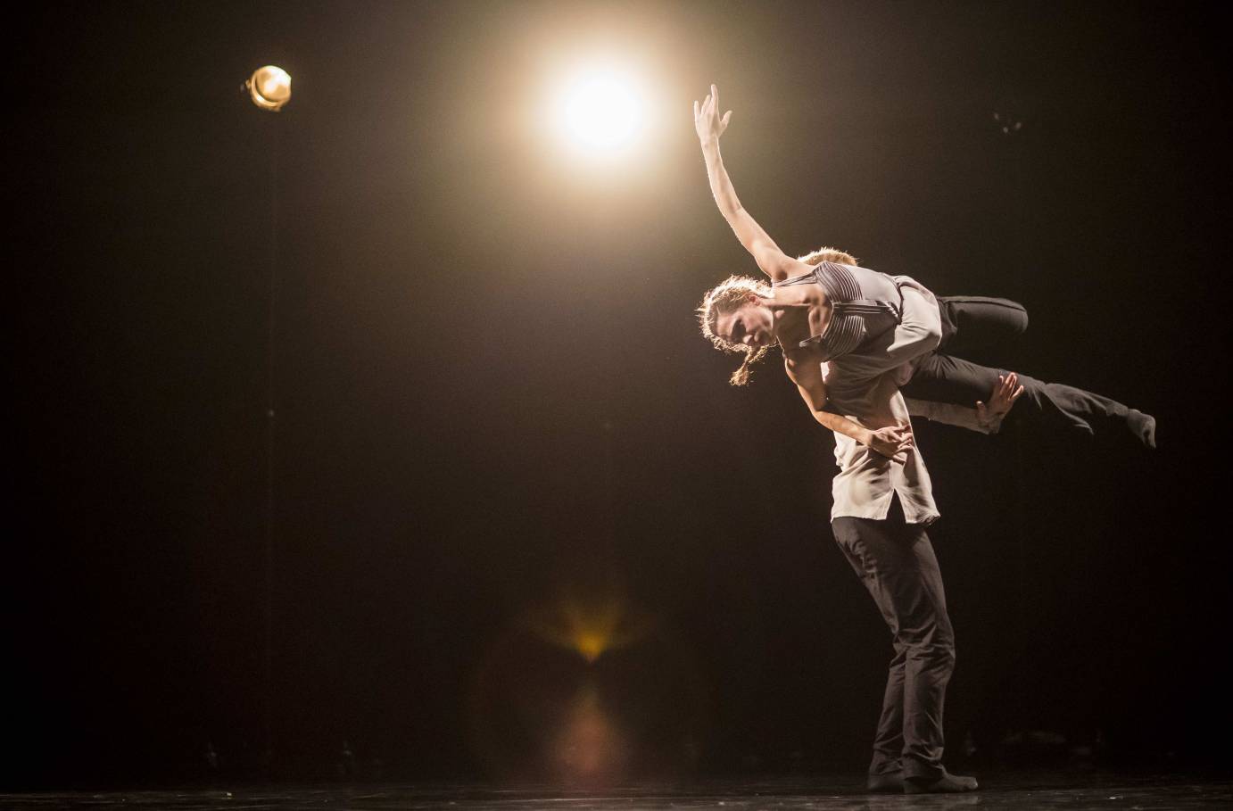 A man lifts a woman as a light glows golden beside them