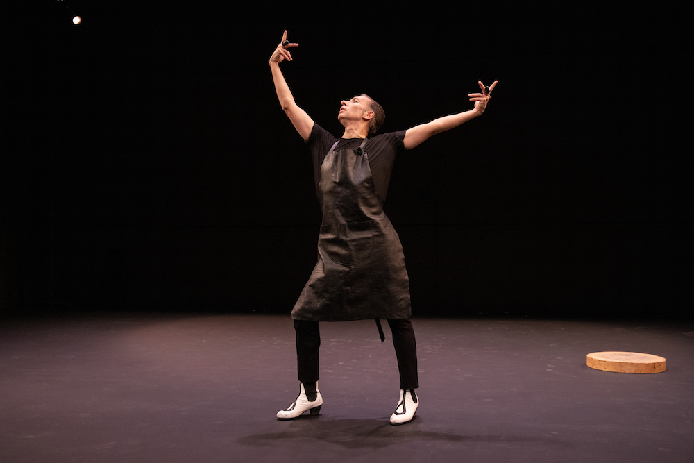 Israel Galvan all in black giving us a profile view... he wears all black, black apron, and white shoes with black decor.. he appears to be preening