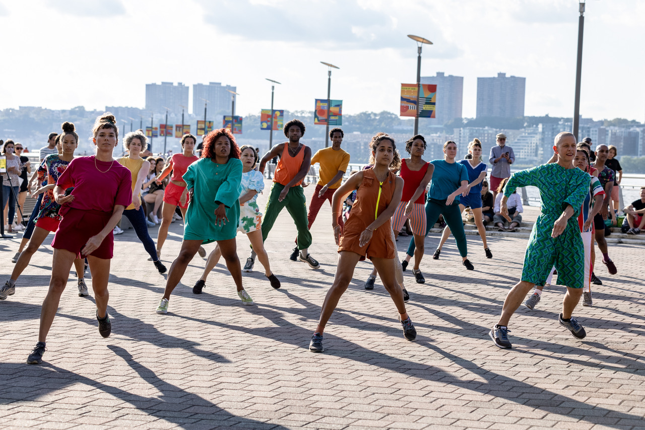 a large group of dancers wearing bright colored clothes dancing in unison