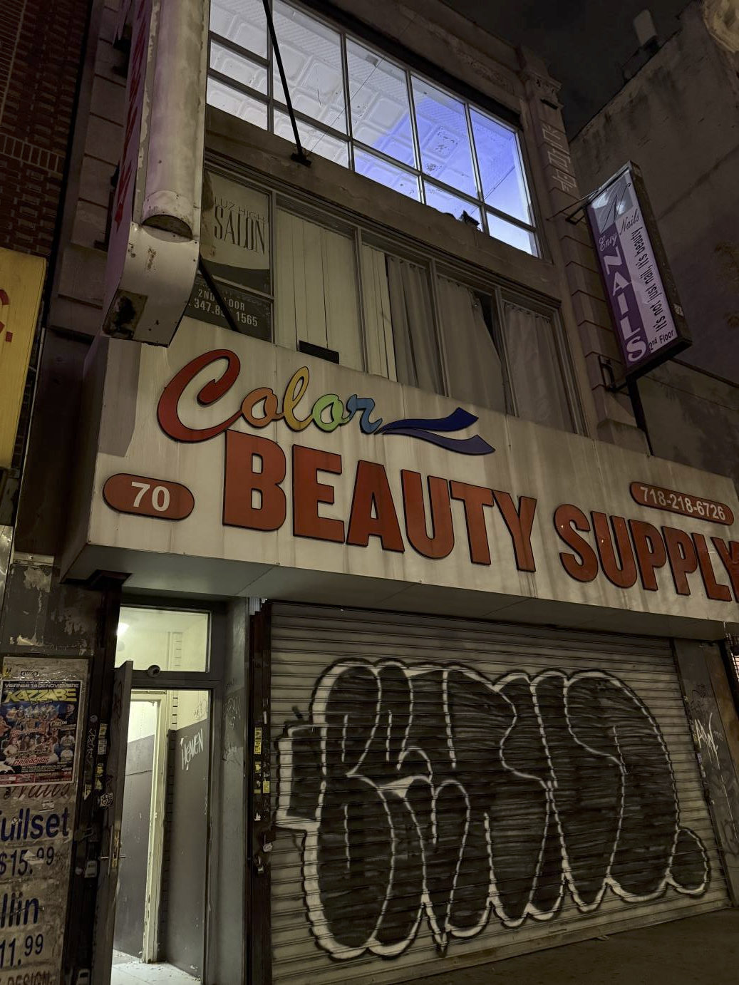 The outside of 70 Graham Street, where PAGEANT is located. The graffiti on the roll down shutter is big black letters outlined in white. Above that are the words in red block letters, BEAUTY SUPPLY.