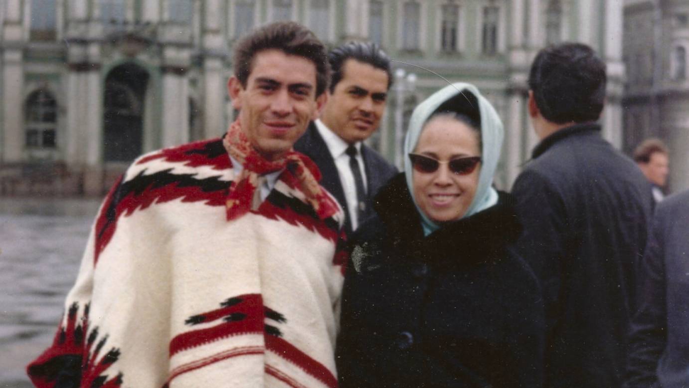 A man in a poncho stands with a woman in a headscarf