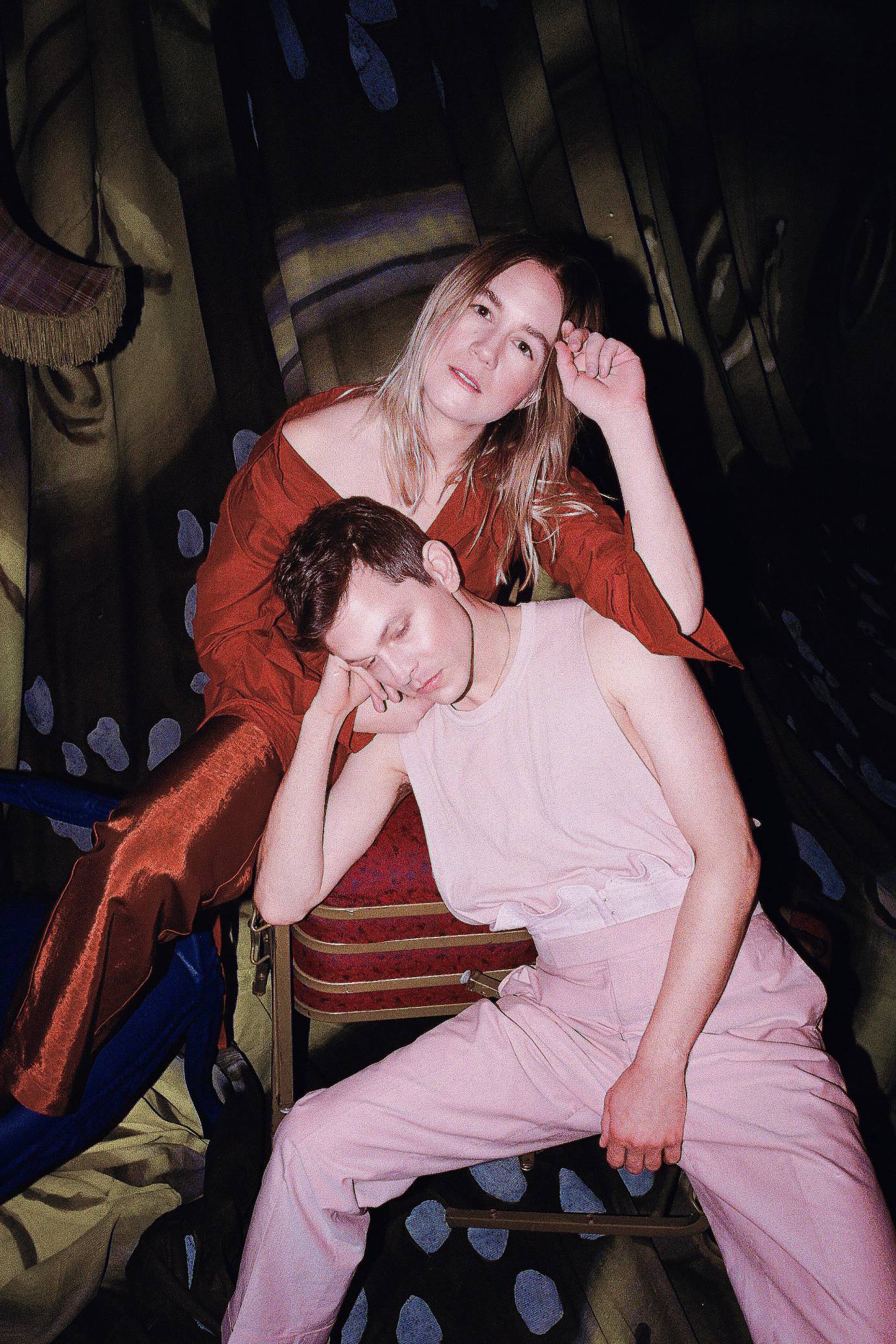 Perfume Genius sits in a chair while Kate Wallich poses beside him