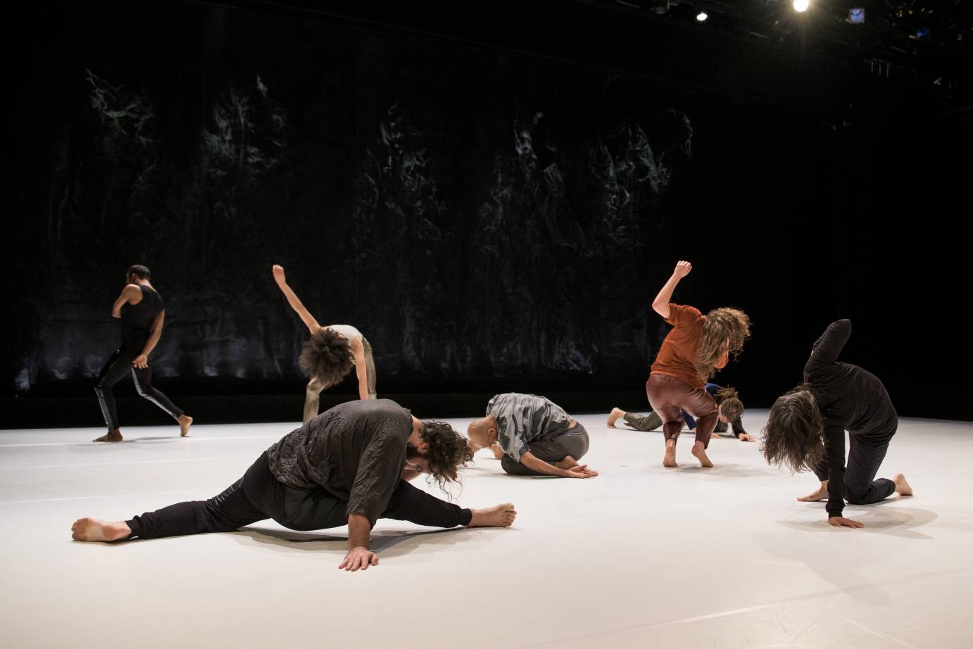 One man downstage affects a split while dancers pose around him