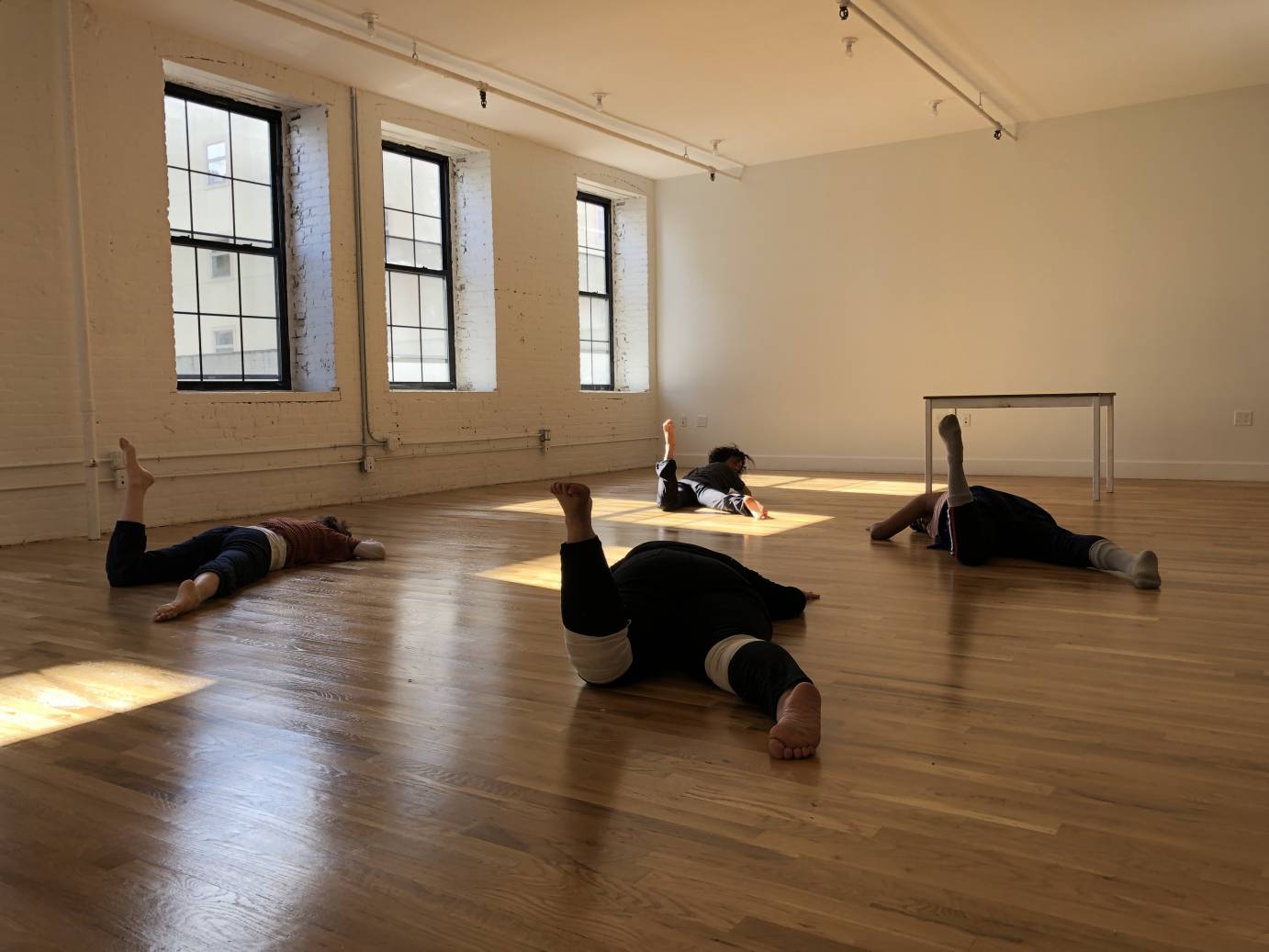 Four women lie prone on their stomachs, one leg  crooked