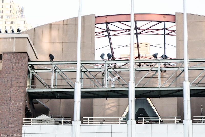 A wide shot of a dancer on a metal walking bridge